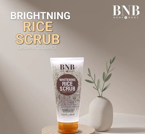 Tube of BNB Brightening Rice Scrub with a plant on a neutral background
