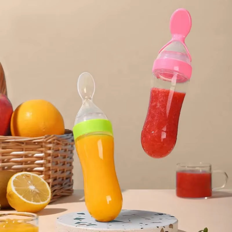 Orange baby bottle and pink fruit feeder with fruits and juice on a table