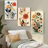 Three floral wall art pieces above a bed in a bedroom setting.