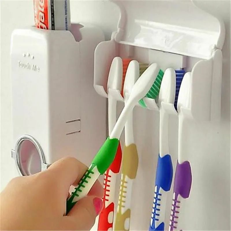 Colorful toothbrushes in a holder with a hand holding one, against a white background.