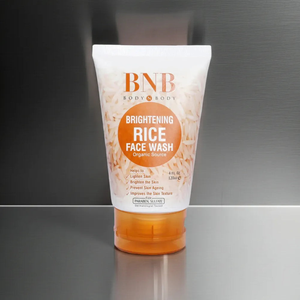 Tube of BNB Brightening Rice Face Wash on a reflective surface with a gray background